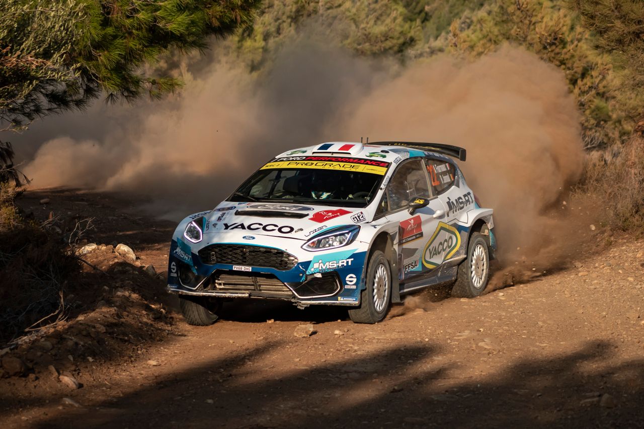 Coche de rally derrapando sobre tierra entre una nube de polvo